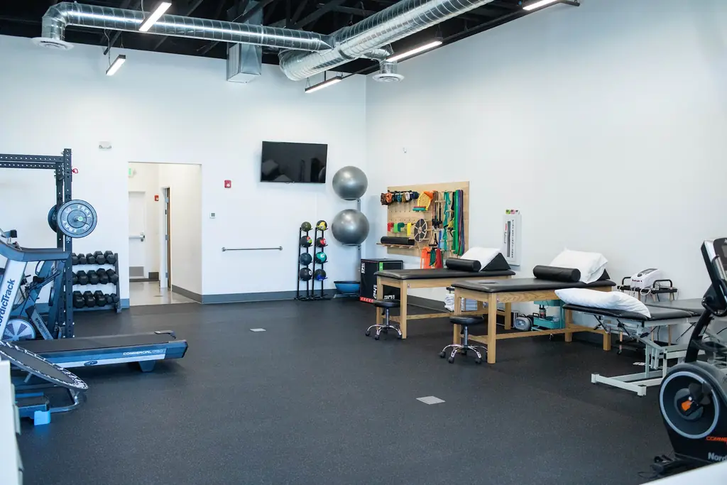 The Fortify Physical Therapy gym floor with treadmills, a dumbbell rack and resistance bands