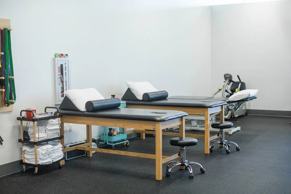 Two treatment tables with bolsters and a supply cart on the Fortify Physical Therapy treatment floor