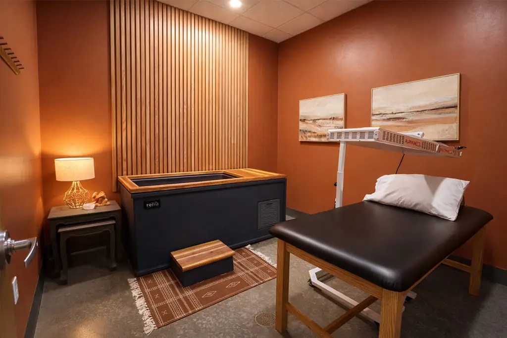 The Fortify Recovery Room: terracotta walls, wood slat panel, cold plunge tub and red light therapy panel