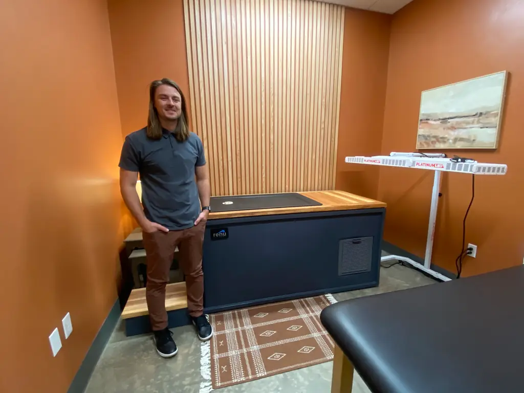 A Fortify staff member beside the cold plunge and red light panel in the Recovery Room